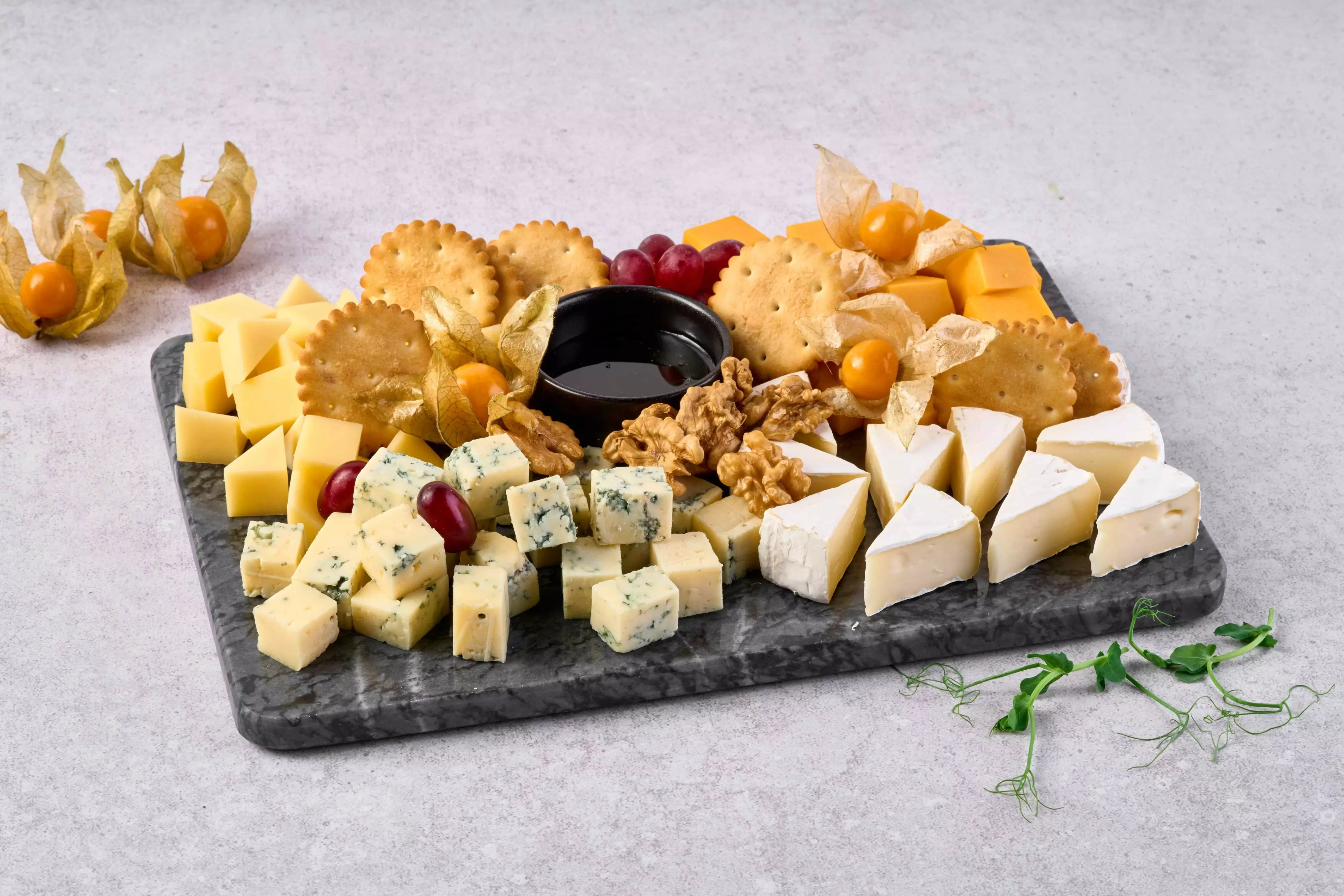 Сырная тарелка — ассорти из популярных сортов сыра с орехами и соусом